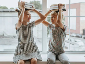 Schulkinder halten ihre Bücher auf dem Kopf fest